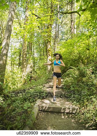 Young woman jogging in forest View Large Photo Image Stock Photo - Young woman jogging in forest. Fotosearch