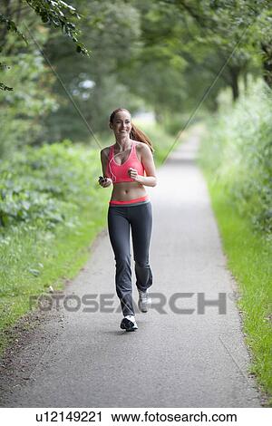 Young woman jogging in park View Large Photo Image Stock Image - Young woman jogging in park. Fotosearch