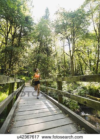 Young woman jogging on footbridge View Large Photo Image Stock Photo - Young woman jogging on footbridge. Fotosearch