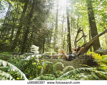 Stock Photo - Young woman lying down on log. Fotosearch