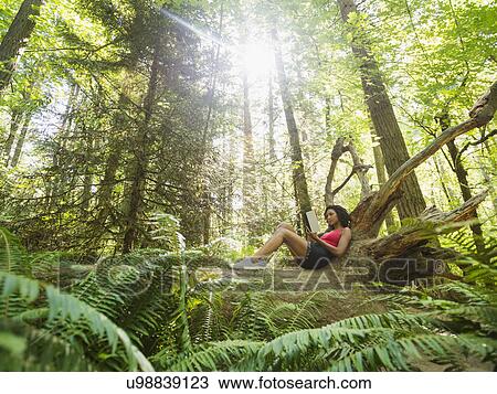 Young woman reading book on log in forest View Large Photo Image Stock Image - Young woman reading book on log in forest. Fotosearch