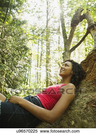 Young woman sitting on log in forest View Large Photo Image Stock Photography - Young woman sitting on log in forest. Fotosearch