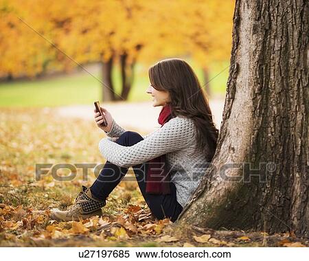 Young woman using cell phone in Central Park View Large Photo Image Stock Photography - Young woman using cell phone in Central Park. Fotosearch
