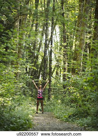 Young women with arms raised in forest View Large Photo Image Stock Photo - Young women with arms raised in forest. Fotosearch