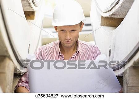 Architect reviewing blueprint at construction site View Large Photo Image Stock Photo - Architect reviewing blueprint at construction site. Fotosearch