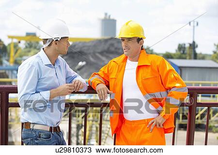 Architects standing against railing at construction site View Large Photo Image Stock Image - Architects standing against railing at construction site. Fotosearch