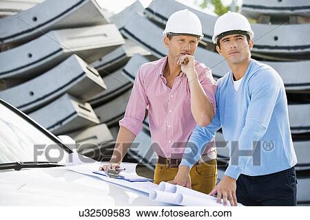 Architects with blueprints on car inspecting site View Large Photo Image Stock Image - Architects with blueprints on car inspecting site. Fotosearch