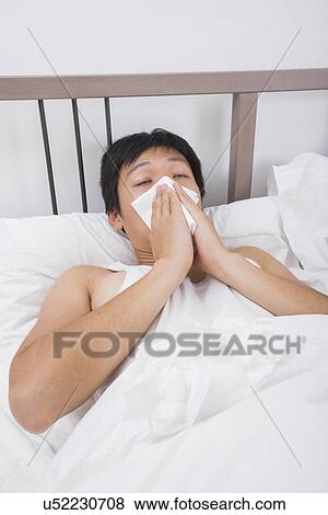 Asian man blowing nose in bed View Large Photo Image Stock Photo - Asian man blowing nose in bed. Fotosearch