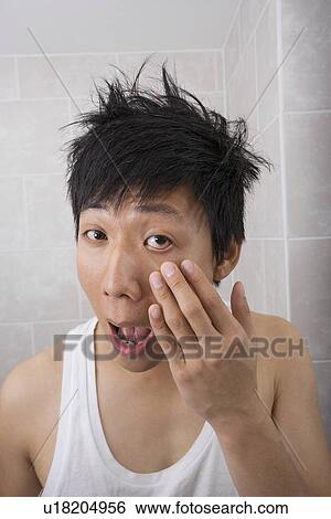 Asian mid adult man inspecting his face in bathroom View Large Photo Image Stock Photograph - Asian mid adult man inspecting his face in bathroom. Fotosearch