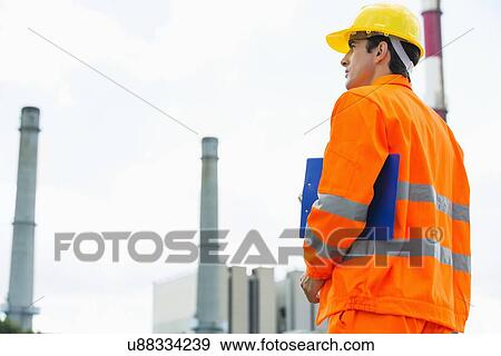 Back view of male architect with clipboard standing at site View Large Photo Image Stock Photo - Back view of male architect with clipboard standing at site. Fotosearch