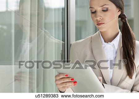 Beautiful businesswoman using digital tablet by glass door View Large Photo Image Stock Image - Beautiful businesswoman using digital tablet by glass door. Fotosearch
