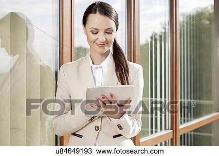 Beautiful businesswoman using digital tablet against office building View Large Photo Image Stock Image - Beautiful businesswoman using digital tablet against office building. Fotosearch
