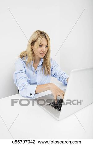 Beautiful young businesswoman using laptop at desk in office View Large Photo Image Stock Image - Beautiful young businesswoman using laptop at desk in office. Fotosearch
