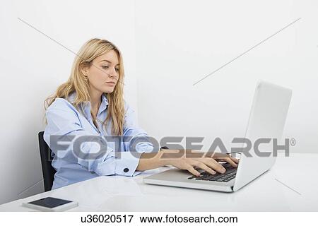 Beautiful young businesswoman using laptop at desk in office View Large Photo Image Stock Photo - Beautiful young businesswoman using laptop at desk in office. Fotosearch
