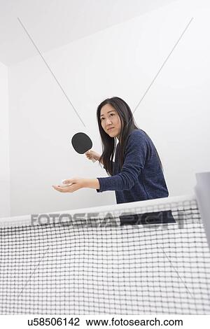 Stock Image - Beautiful young woman preparing to serve ping pong ball. Fotosearch