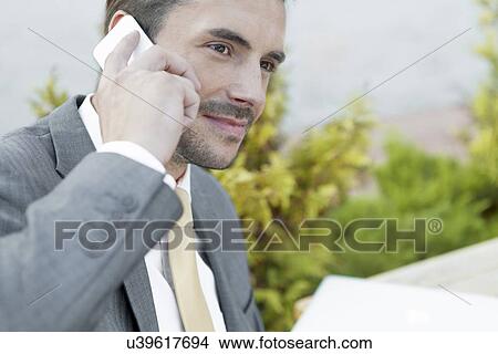 Businessman answering cell phone outdoors View Large Photo Image Picture - Businessman answering cell phone outdoors. Fotosearch