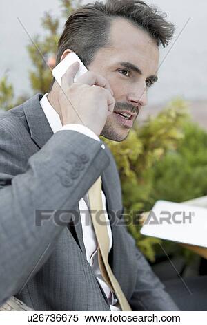 Stock Photography - Businessman answering cell phone outdoors. Fotosearch