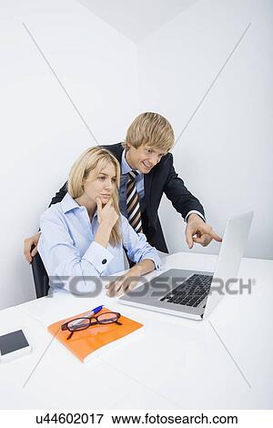 Businessman showing something to coworker on laptop in office View Large Photo Image Stock Photo - Businessman showing something to coworker on laptop in office. Fotosearch