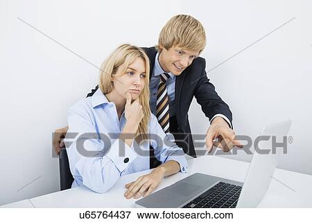 Businessman showing something to coworker on laptop in office View Large Photo Image Stock Photo - Businessman showing something to coworker on laptop in office. Fotosearch