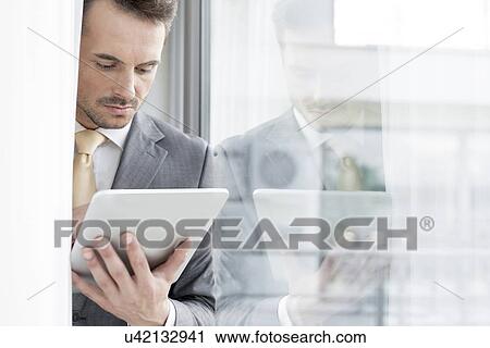 Businessman using digital tablet in office View Large Photo Image Stock Image - Businessman using digital tablet in office. Fotosearch