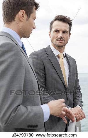 Businessmen having a discussion on terrace View Large Photo Image Stock Image - Businessmen having a discussion on terrace. Fotosearch