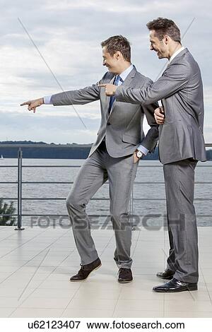 Stock Photo - Businessmen pointing at something against sky. Fotosearch