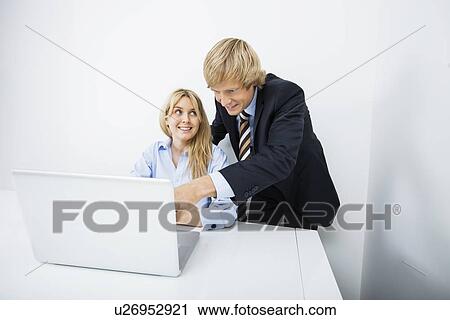 Stock Image - Businesspeople discussing over laptop in office. Fotosearch