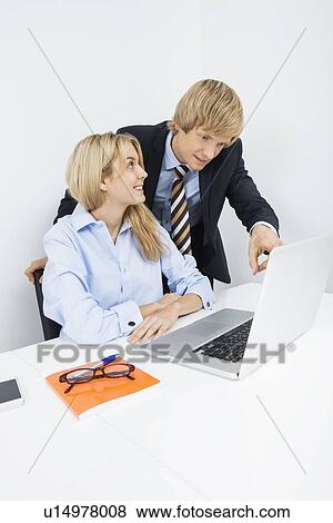 Businesspeople discussing over laptop at desk in office View Large Photo Image Stock Photo - Businesspeople discussing over laptop at desk in office. Fotosearch