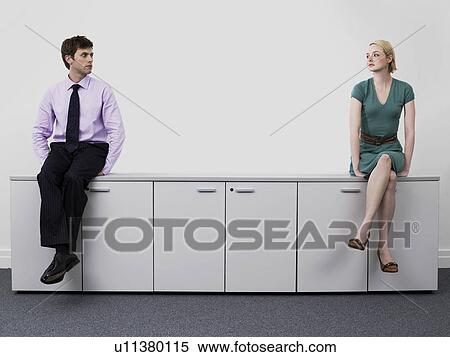Businesspeople sitting on office cabinets View Large Photo Image Stock Photography - Businesspeople sitting on office cabinets. Fotosearch