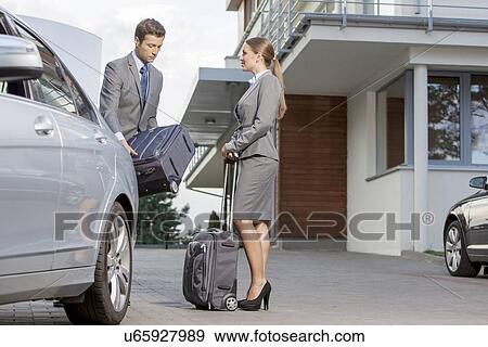 Businesspeople unloading luggage from car outside hotel View Large Photo Image Stock Photo - Businesspeople unloading luggage from car outside hotel. Fotosearch