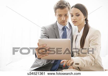 Stock Image - Businesspeople using digital tablet in hotel. Fotosearch