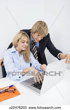 Businesspeople using laptop at desk in office View Large Photo Image Stock Image - Businesspeople using laptop at desk in office. Fotosearch
