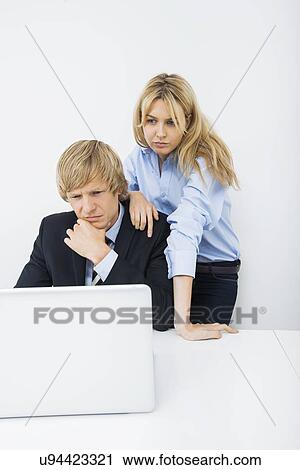 Businesspeople using laptop at desk in office View Large Photo Image Stock Image - Businesspeople using laptop at desk in office. Fotosearch