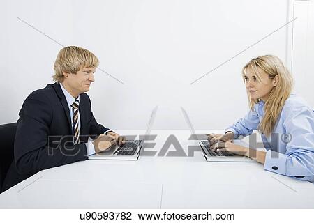 Businesspeople with laptops looking at each other in office View Large Photo Image Stock Image - Businesspeople with laptops looking at each other in office. Fotosearch