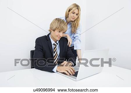 Businesspeople working on laptop at desk in office View Large Photo Image Picture - Businesspeople working on laptop at desk in office. Fotosearch