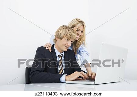 Businesspeople working on laptop at desk in office View Large Photo Image Stock Image - Businesspeople working on laptop at desk in office. Fotosearch