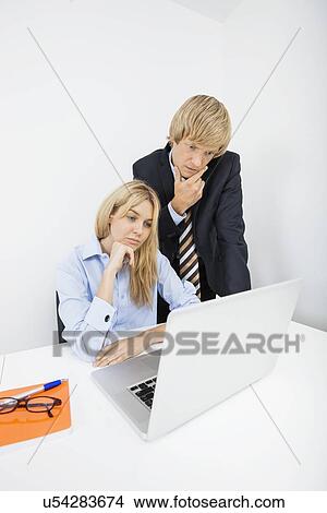 Picture - Businesspeople working on laptop in office. Fotosearch