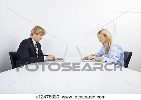 Businesspeople working on laptops in office View Large Photo Image Stock Image - Businesspeople working on laptops in office. Fotosearch