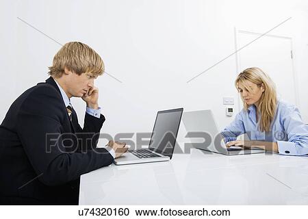 Businesspeople working on laptops in office View Large Photo Image Stock Image - Businesspeople working on laptops in office. Fotosearch