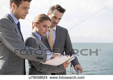 Picture - Businessteam with book standing on terrace against sky. Fotosearch