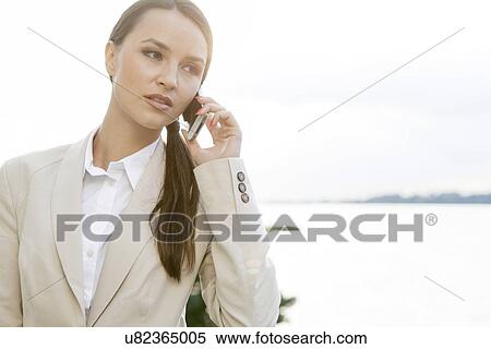 Businesswoman answering cell phone outdoors View Large Photo Image Stock Photography - Businesswoman answering cell phone outdoors. Fotosearch