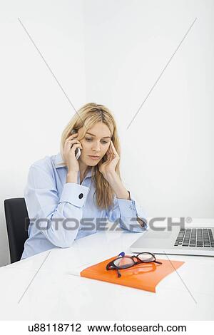 Businesswoman answering smart phone in office View Large Photo Image Stock Image - Businesswoman answering smart phone in office. Fotosearch