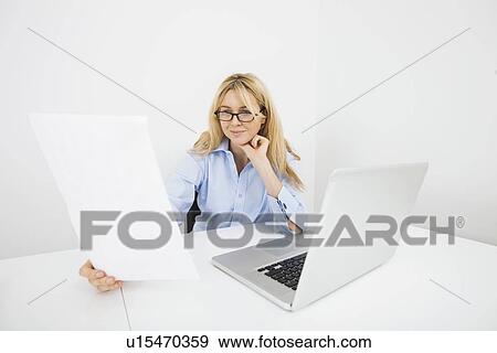Stock Photo - Businesswoman reading document in office. Fotosearch