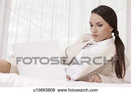 Stock Photo - Businesswoman using laptop in hotel room. Fotosearch