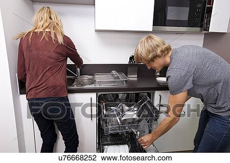 Stock Image - Caucasian couple working together in kitchen. Fotosearch