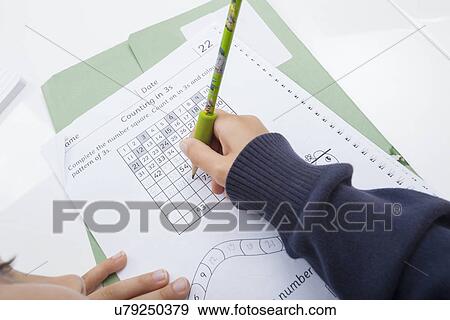 Stock Photo - Close-up of girl's hand writing numbers on document. Fotosearch
