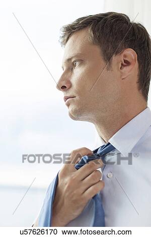 Close-up of pensive businessman loosening necktie in hotel View Large Photo Image Stock Image - Close-up of pensive businessman loosening necktie in hotel. Fotosearch