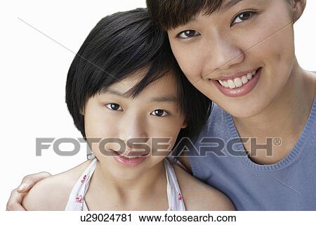 Stock Image - Close-up of sisters smiling over white background. Fotosearch