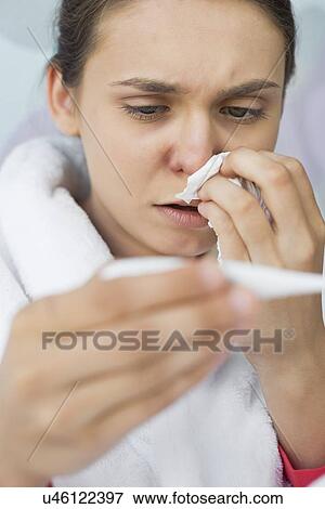 Stock Photo - Close-up of worried woman taking her temperature. Fotosearch