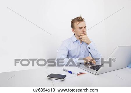 Concentrated businessman using laptop at desk in office View Large Photo Image Stock Image - Concentrated businessman using laptop at desk in office. Fotosearch